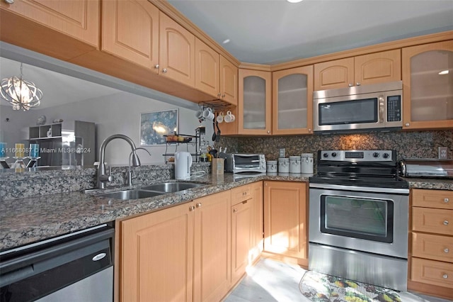 kitchen featuring sink, backsplash, a chandelier, appliances with stainless steel finishes, and dark stone countertops