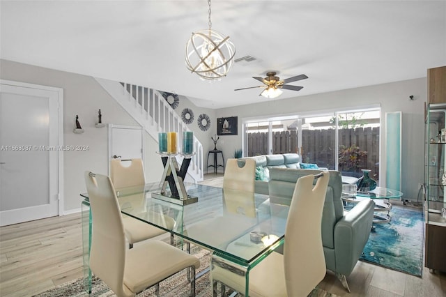 dining area with ceiling fan with notable chandelier and light hardwood / wood-style floors