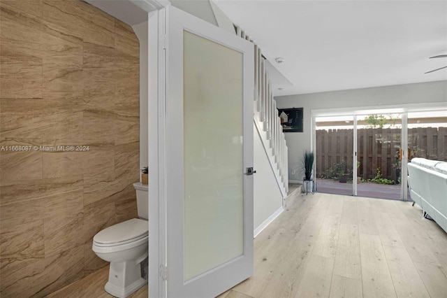 bathroom featuring tile walls, hardwood / wood-style flooring, and toilet