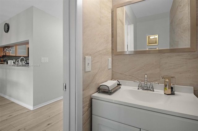 bathroom with tile walls, vanity, and hardwood / wood-style floors