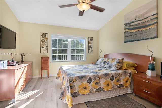 bedroom featuring light wood-type flooring, vaulted ceiling, and ceiling fan