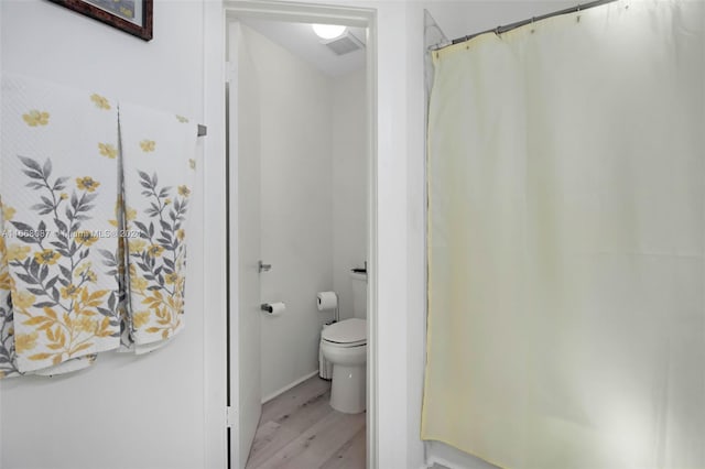 bathroom featuring toilet, a shower with shower curtain, and hardwood / wood-style flooring