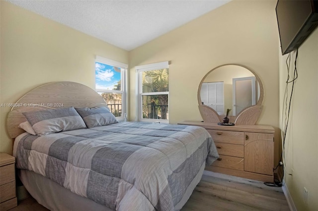 bedroom with light wood-type flooring and lofted ceiling