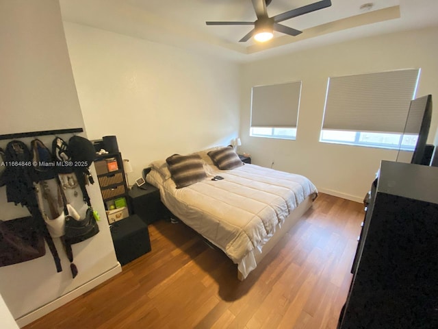 bedroom featuring a tray ceiling, ceiling fan, and wood-type flooring