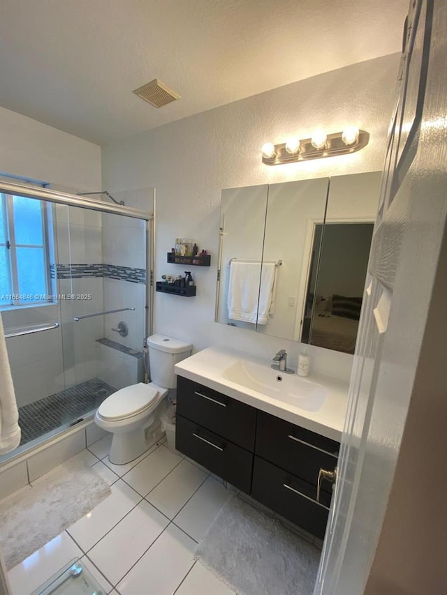 bathroom featuring tile patterned flooring, vanity, toilet, and an enclosed shower