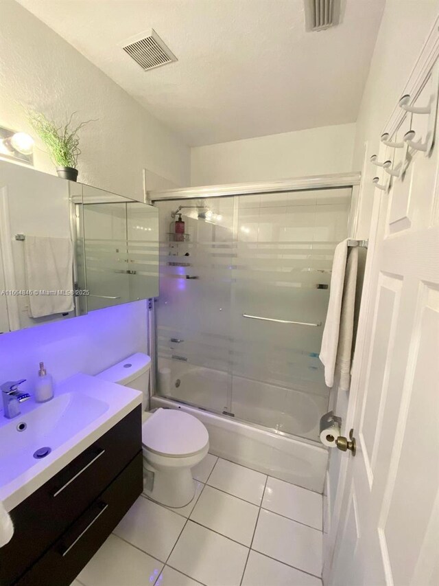 full bathroom with tile patterned flooring, toilet, vanity, and combined bath / shower with glass door