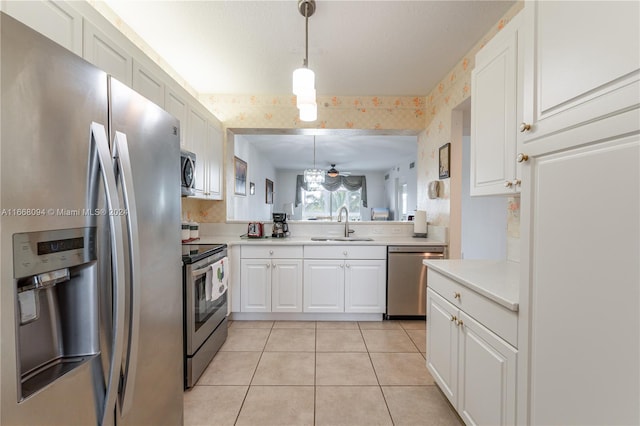 kitchen with appliances with stainless steel finishes, light tile patterned flooring, white cabinetry, decorative light fixtures, and sink