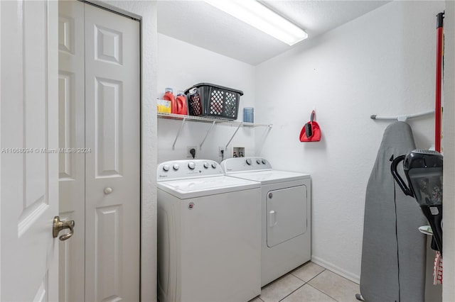 laundry area with a textured ceiling, light tile patterned floors, and washing machine and dryer