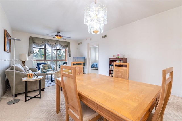 dining space featuring ceiling fan with notable chandelier and light carpet