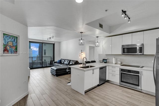 kitchen with white cabinetry, kitchen peninsula, stainless steel appliances, decorative light fixtures, and sink