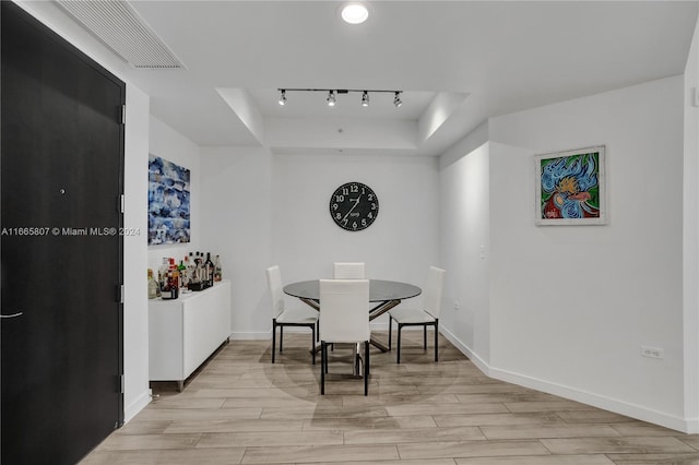 dining room with rail lighting and light hardwood / wood-style flooring