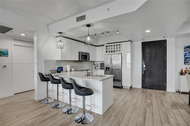 kitchen with pendant lighting, sink, white cabinets, kitchen peninsula, and appliances with stainless steel finishes