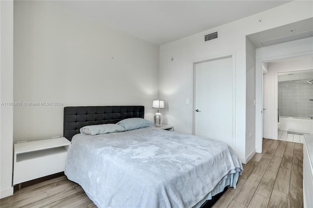 bedroom featuring light wood-type flooring and ensuite bathroom