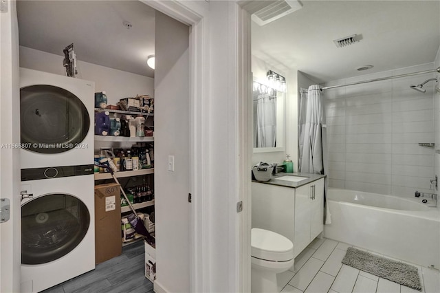 full bathroom featuring stacked washing maching and dryer, shower / bath combo with shower curtain, vanity, toilet, and tile patterned floors