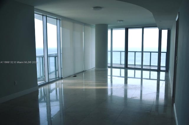 unfurnished room featuring a wall of windows, tile patterned flooring, a water view, and a healthy amount of sunlight