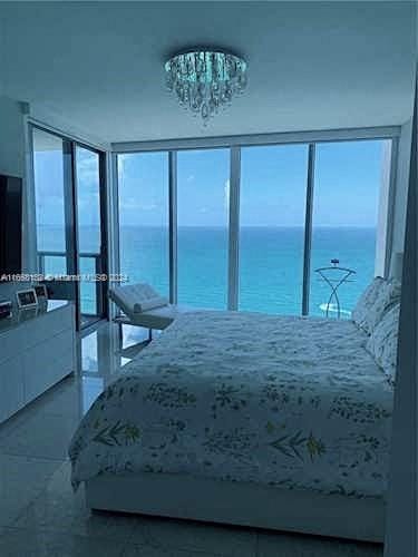 bedroom with a water view, multiple windows, and a chandelier