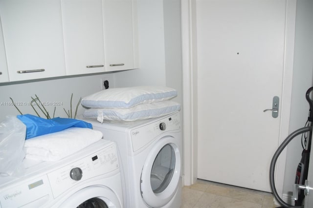 laundry area with washer and clothes dryer, light tile patterned floors, and cabinets