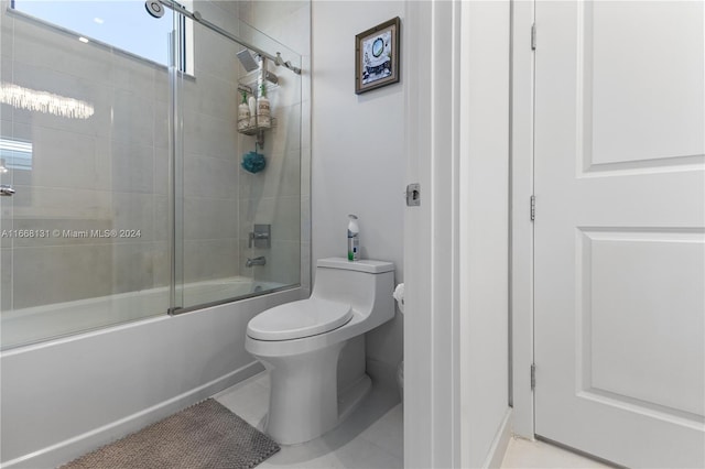 bathroom featuring shower / bath combination with glass door, tile patterned flooring, and toilet