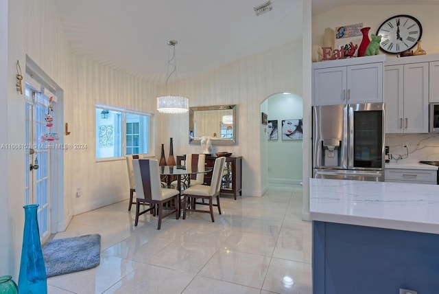 dining space featuring vaulted ceiling, light tile patterned floors, and a notable chandelier