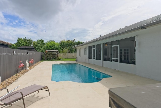 view of pool with a sunroom and a patio area