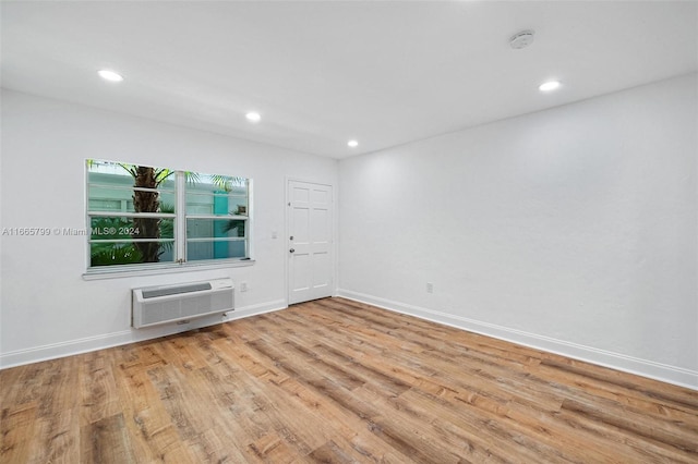 empty room with light hardwood / wood-style floors and a wall unit AC