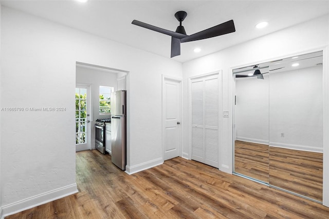 unfurnished bedroom with stainless steel fridge, two closets, dark hardwood / wood-style flooring, and ceiling fan