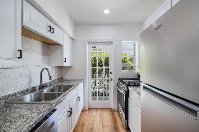 kitchen with appliances with stainless steel finishes, decorative backsplash, white cabinetry, and light hardwood / wood-style flooring