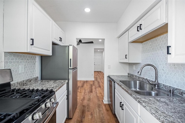 kitchen featuring dark wood-type flooring, sink, white cabinetry, stainless steel appliances, and backsplash