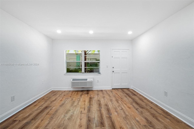 unfurnished room with wood-type flooring and a wall unit AC