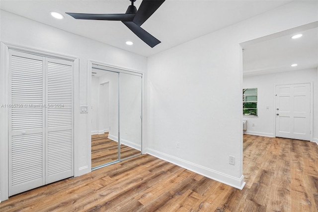 unfurnished bedroom with multiple closets, ceiling fan, and hardwood / wood-style flooring