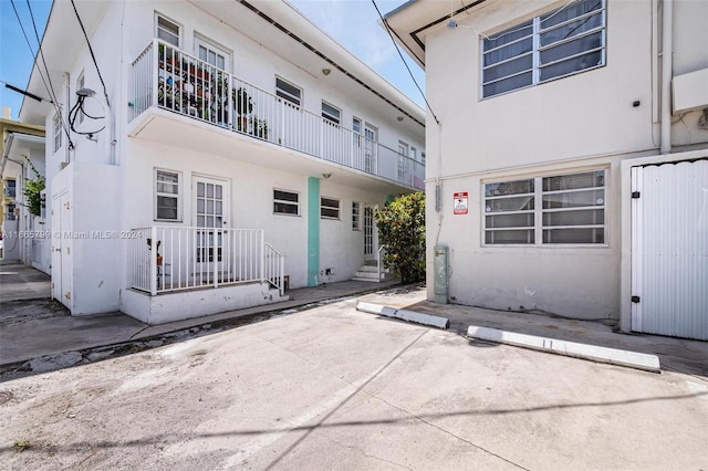 view of exterior entry featuring a balcony and a patio