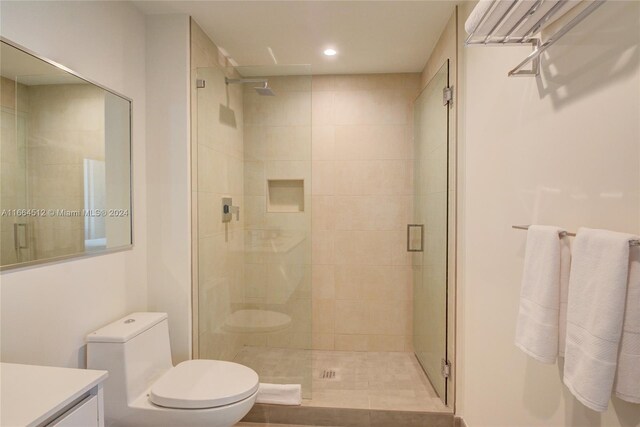 bathroom featuring tile patterned flooring, vanity, toilet, and a shower with door