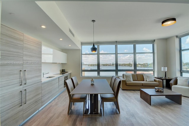 dining room with a water view, hardwood / wood-style flooring, expansive windows, and sink