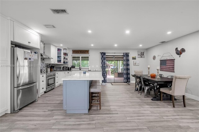 kitchen featuring appliances with stainless steel finishes, a breakfast bar, white cabinets, a center island, and light hardwood / wood-style flooring