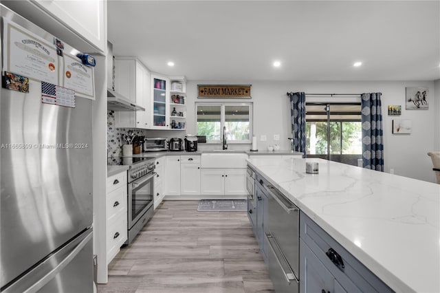 kitchen with light stone counters, stainless steel appliances, plenty of natural light, and white cabinets