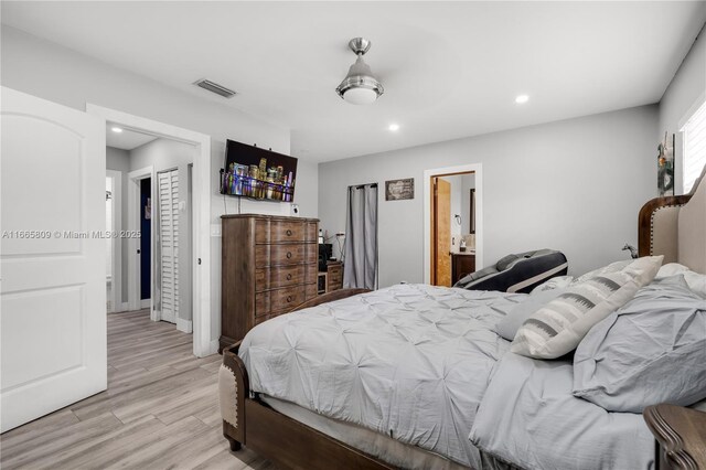 bedroom featuring light hardwood / wood-style flooring and ensuite bath