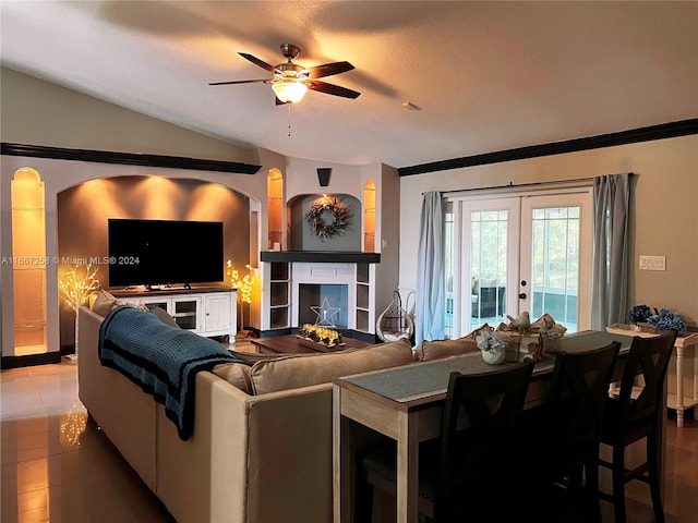 living room with ceiling fan, tile patterned flooring, a textured ceiling, a tiled fireplace, and vaulted ceiling