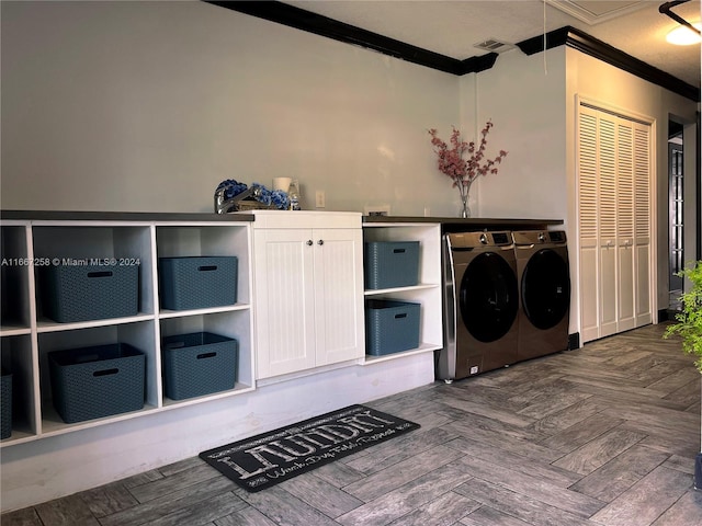 clothes washing area with washer and clothes dryer, crown molding, dark parquet floors, and cabinets