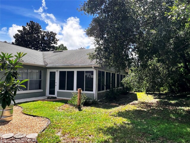 rear view of house with a lawn and a sunroom