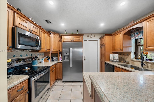 kitchen featuring decorative backsplash, light tile patterned floors, stainless steel appliances, a textured ceiling, and sink