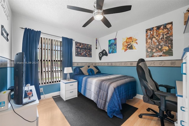 bedroom with light hardwood / wood-style flooring, ceiling fan, and a textured ceiling