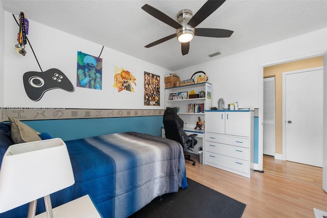 bedroom with a textured ceiling, light hardwood / wood-style floors, and ceiling fan