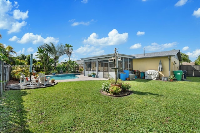 back of house featuring a fenced in pool, a sunroom, and a lawn