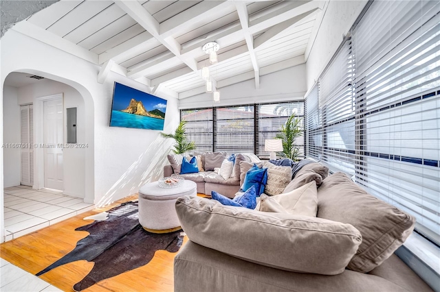 tiled living room with lofted ceiling with beams and electric panel