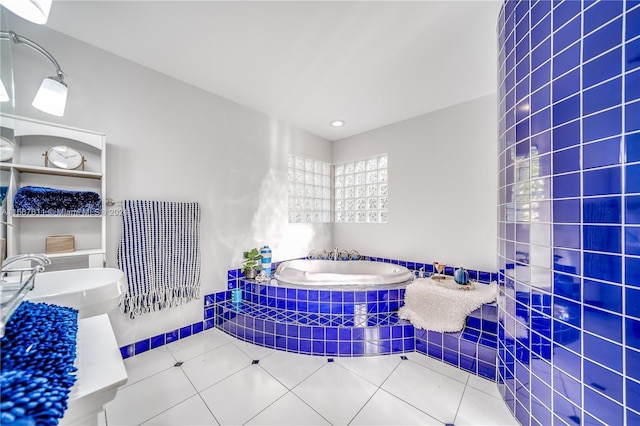 bathroom with a relaxing tiled tub, tile patterned floors, and tile walls