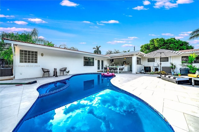 view of swimming pool featuring a patio area, central air condition unit, and an in ground hot tub