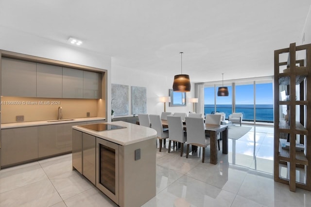 kitchen featuring sink, gray cabinetry, decorative light fixtures, black electric cooktop, and a water view