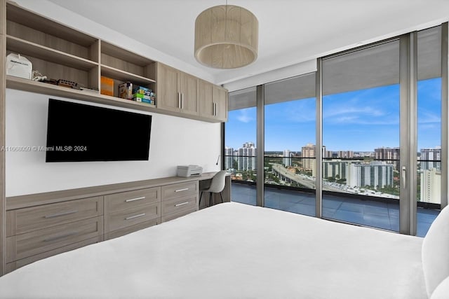 bedroom featuring a wall of windows, built in desk, and access to exterior