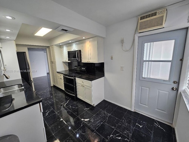 kitchen with an AC wall unit, white cabinets, black appliances, and sink