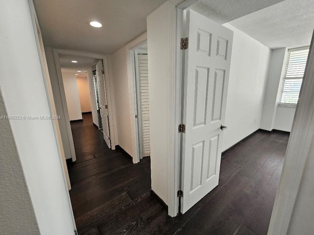 hallway with a textured ceiling and dark wood-type flooring